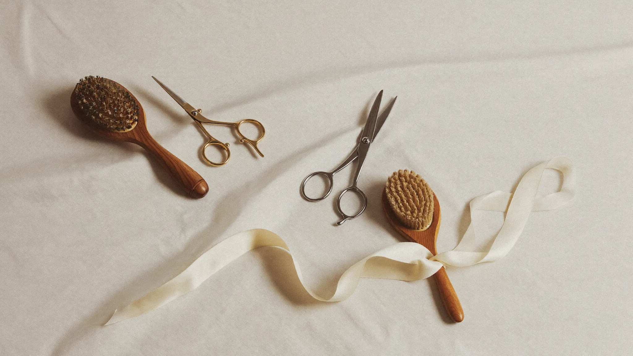 Salon shears, comb and brush arranged on ivory linen