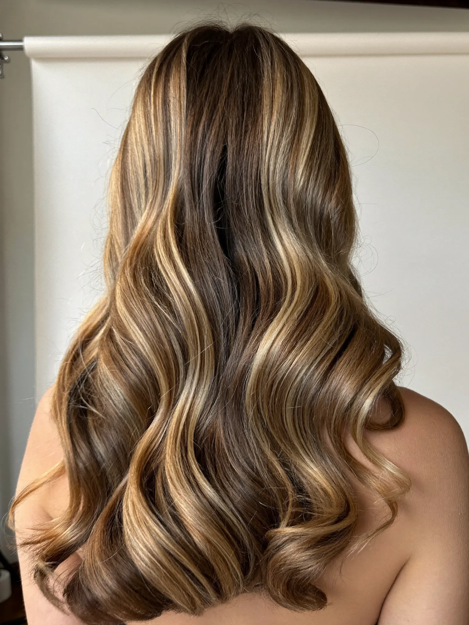 Long glossy balayage waves with warm honey-blonde dimension, styled at Top Knot Hair Studio