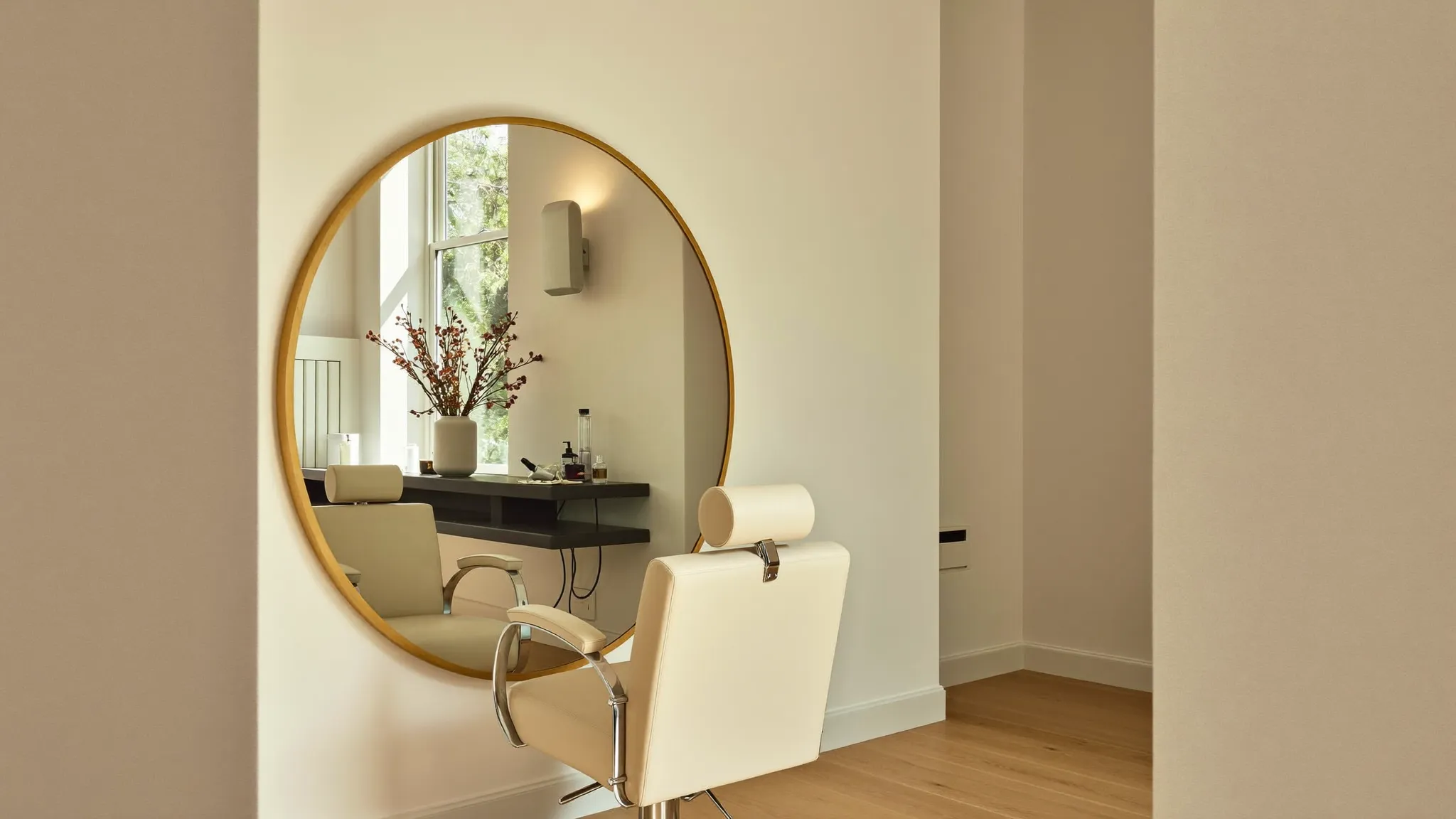 The warm, sunlit interior of Top Knot Hair Studio with gold mirrors and cream chairs